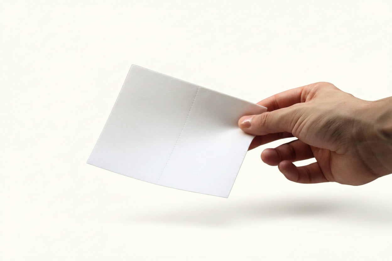 A hand holding a blue bird detergent sheet.